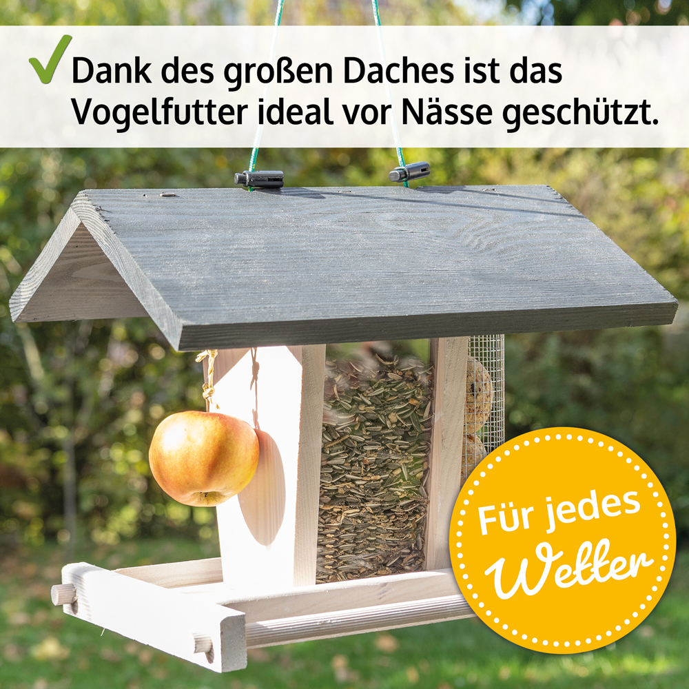 Vogelhaus Bird Kitchen mit großem grauem Dach das das Vogelfutter vor Nässe schützt an der Seite hängt ein Apfel geeignet für jedes Wetter