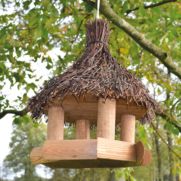 Vogelhaus Sweet Home mit einem naturgetreuen Reisigdach und einem stabilen Kiefernholzrahmen in einem Baum hängend